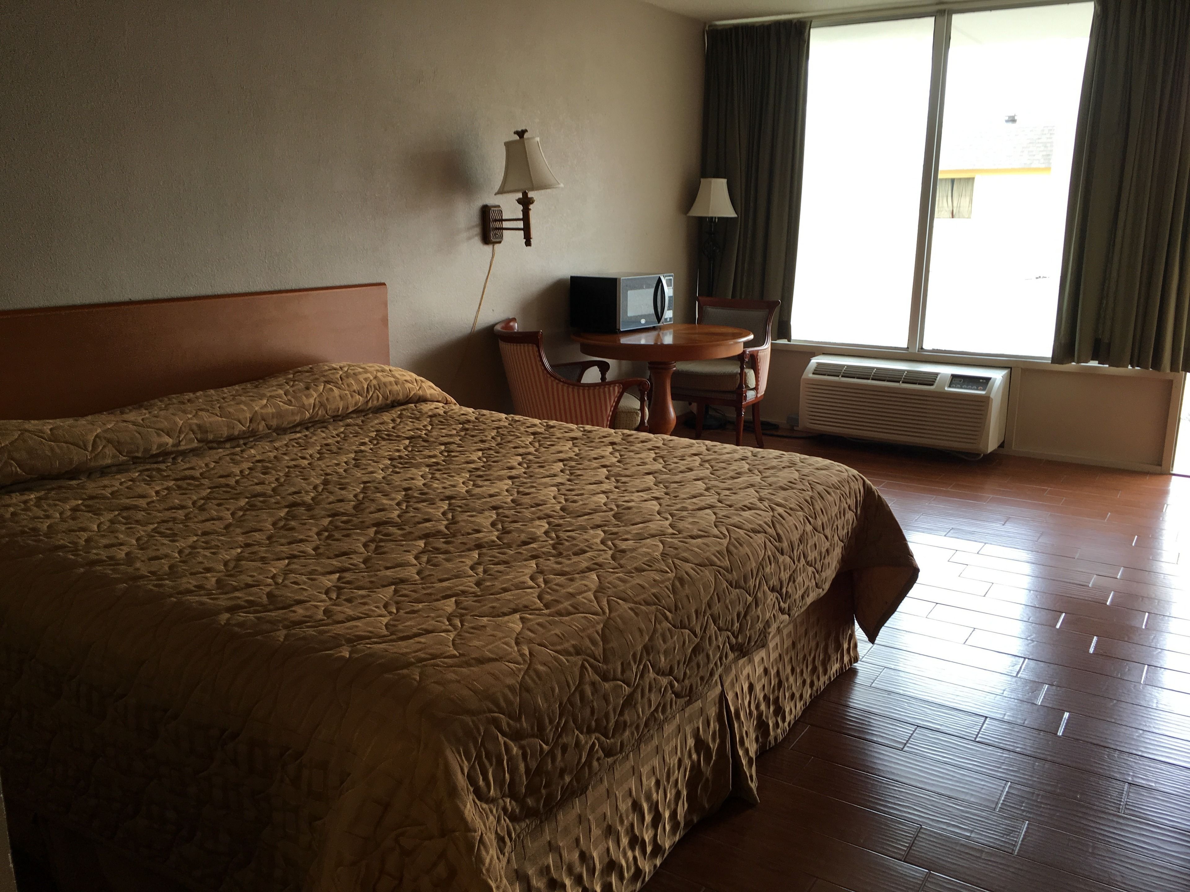 Habitació d'hotel amb un llit gran, una taula de treball, una cadira, una televisió i un aire condicionat.