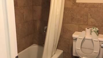 A bathroom with a bathtub, toilet, and shower curtain.