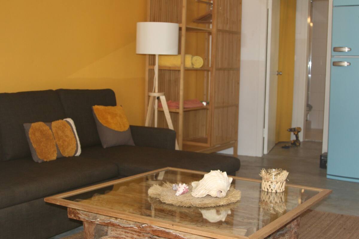 Un salon avec un canapé marron foncé, une table basse en verre et une bibliothèque en bois.