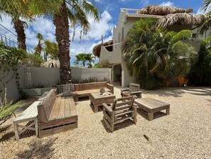 Un espace extérieur aménagé avec du mobilier en bois et une structure recouverte d’un toit de chaume.