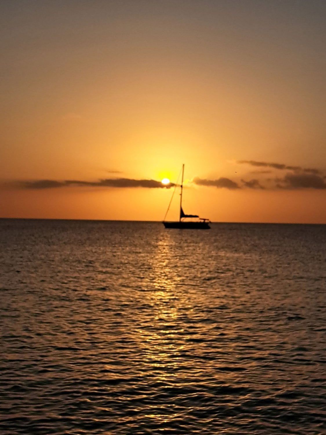 A sailboat on calm water during sunset.