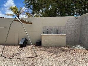 A small outdoor area with a concrete bench, a metal swing, and a tiled wall. - BnBBonaire (Kralendijk)