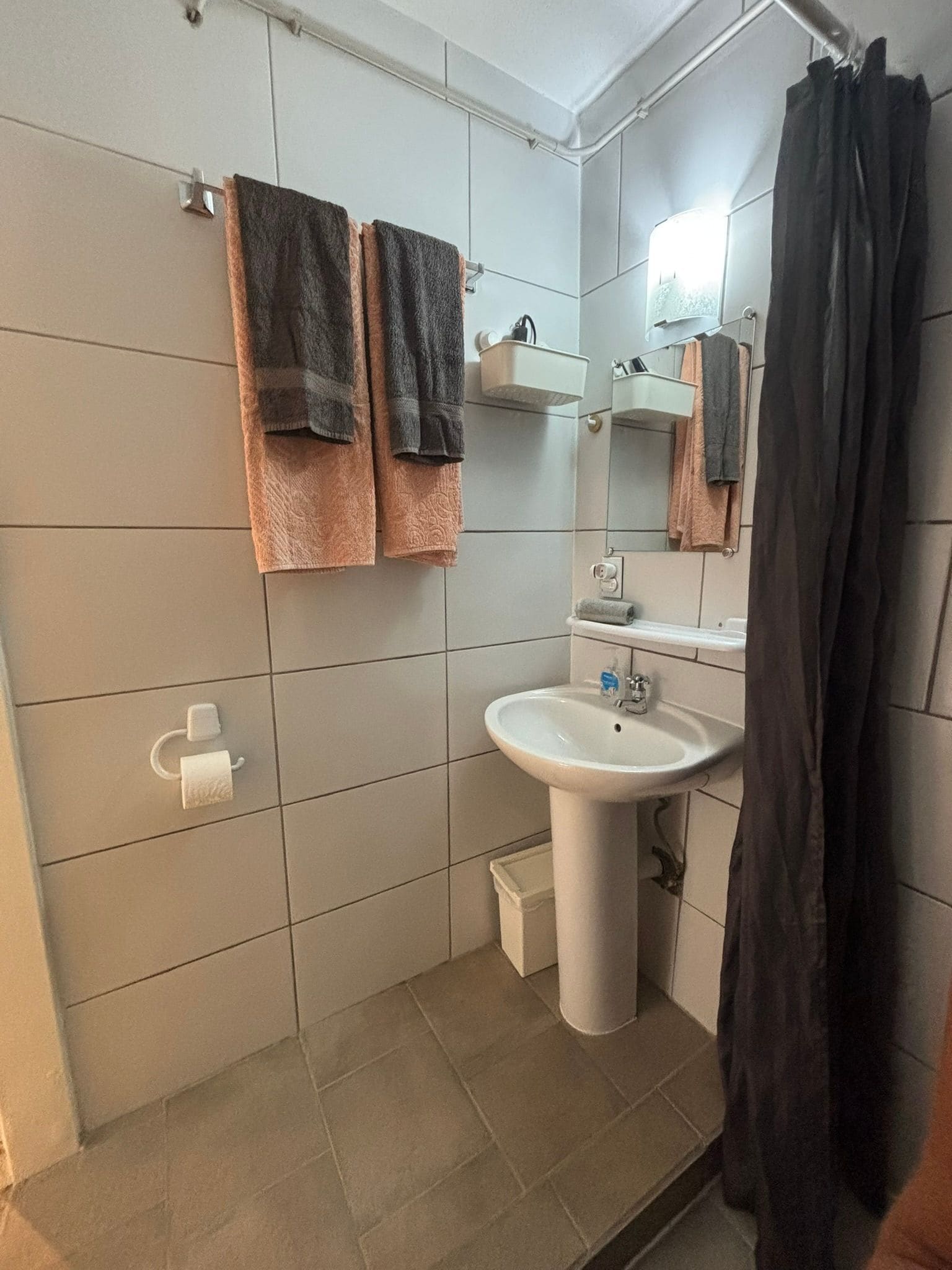 A bathroom with a sink, mirror, towel rack, and a shower curtain.