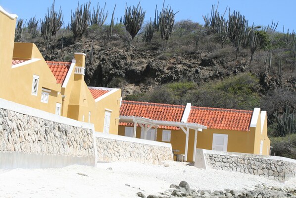 A coastal building with a red-tiled roof, white balconies, and a stone wall. - BnBBonaire (Kralendijk)