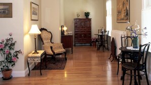 Amplia sala de estar con pisos de madera, una araña, una chimenea y un comedor con muebles de madera.