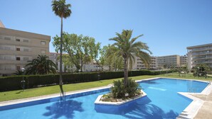Una piscina rodeada de palmeras y un césped cuidado.