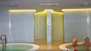 Ein Spa-Bereich mit zwei Whirlpools und einer gefliesten Wand.