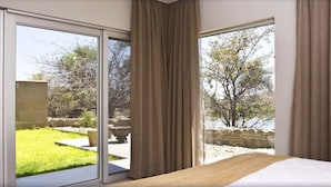 Ein Schlafzimmer mit einer großen SchiebeglasTür, die auf eine Terrasse führt.