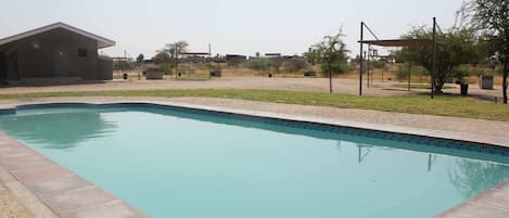 Piscina com borda azulejada, rodeada por um deck de concreto.