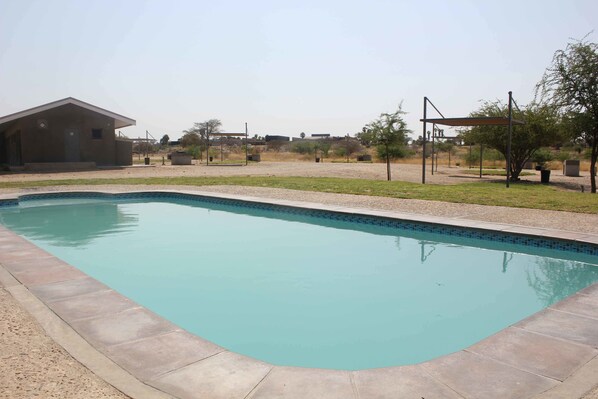 A swimming pool with a tiled edge, surrounded by a concrete deck.
