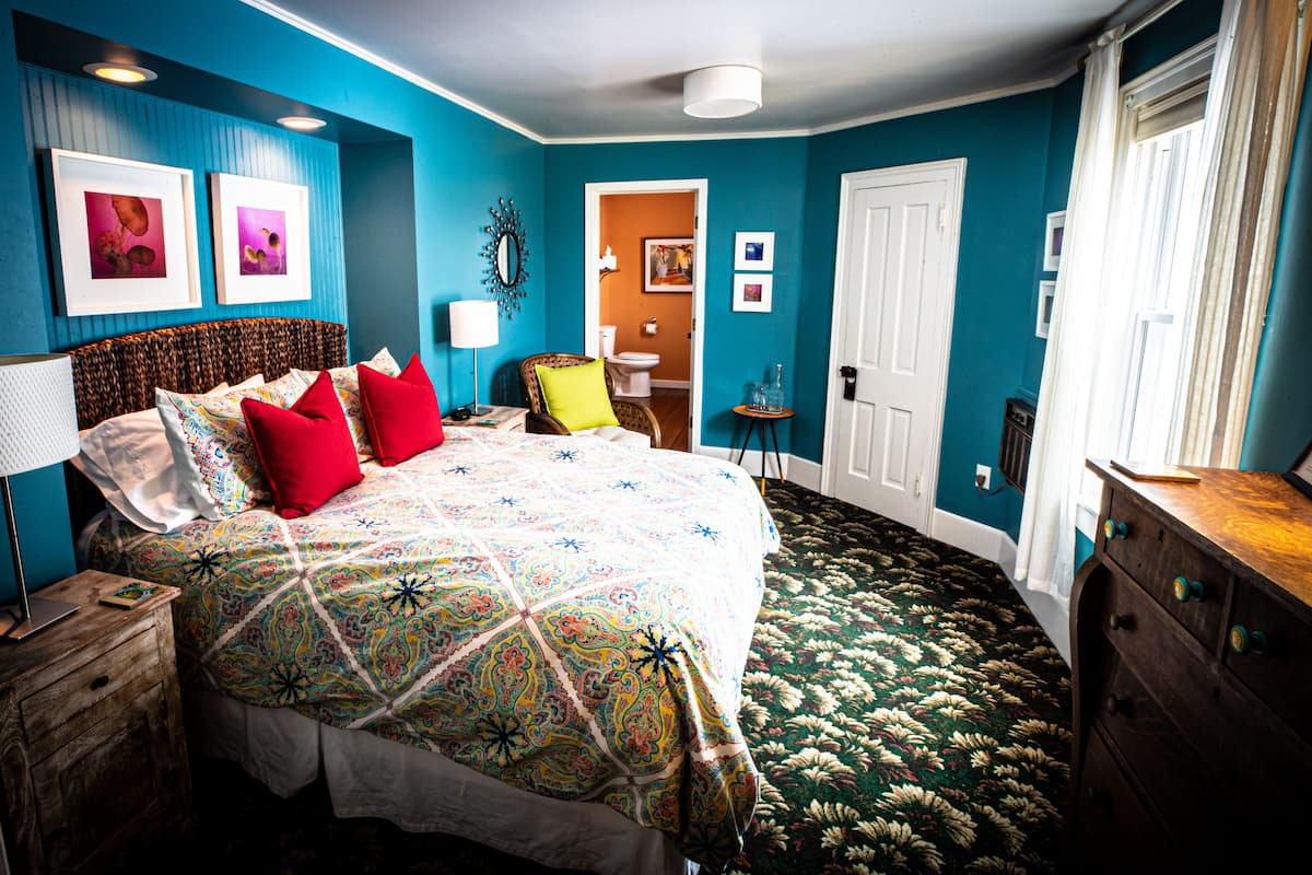 A bedroom with a bed, a chair, a dresser, and a door.