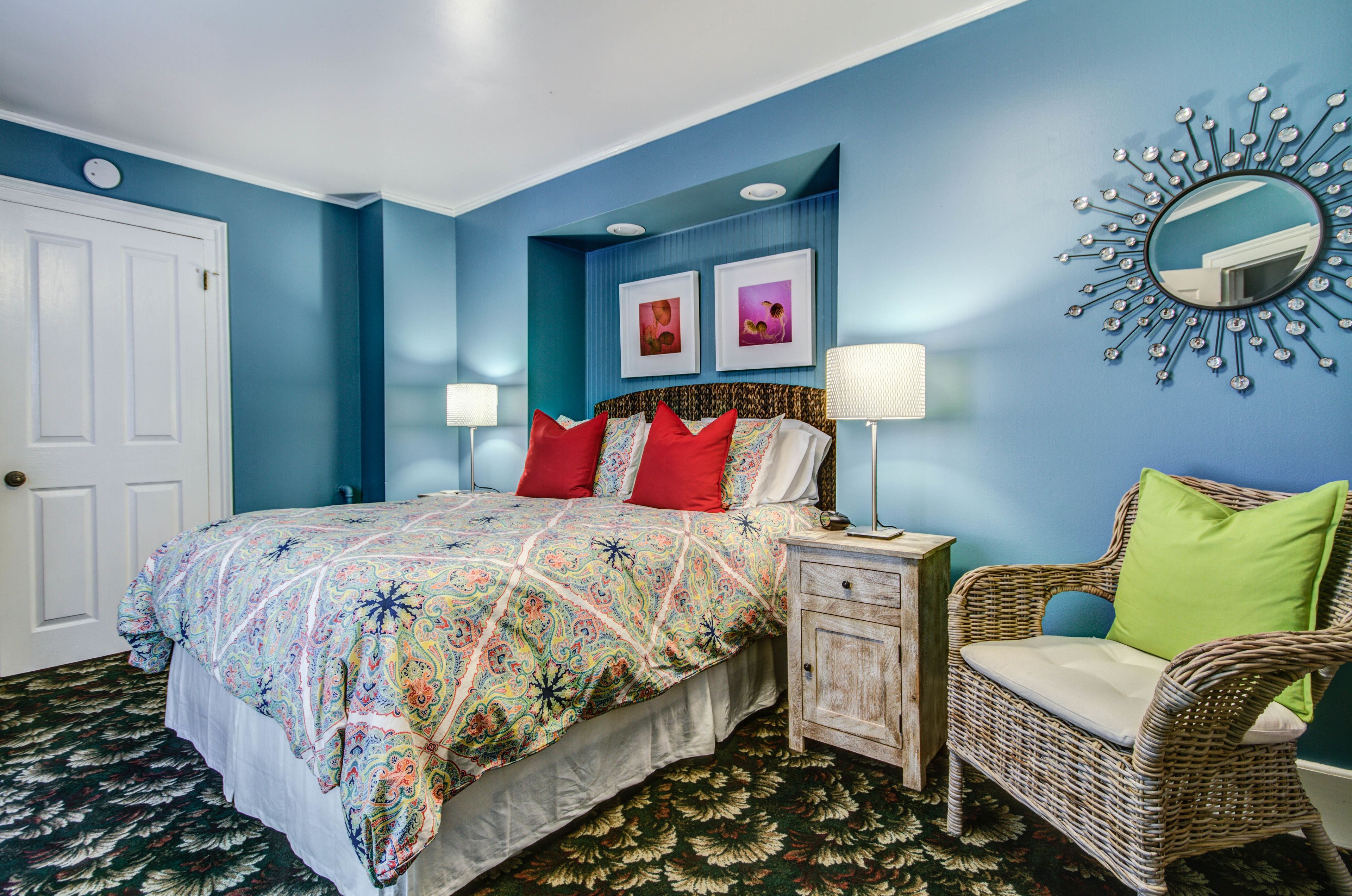 Quarto com cama, mesa de cabeceira, cadeira e decoração na parede.