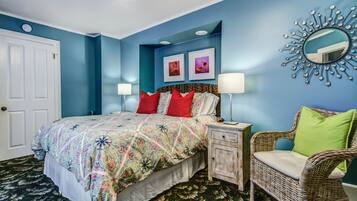 Quarto com cama, mesa de cabeceira, cadeira e decoração na parede.