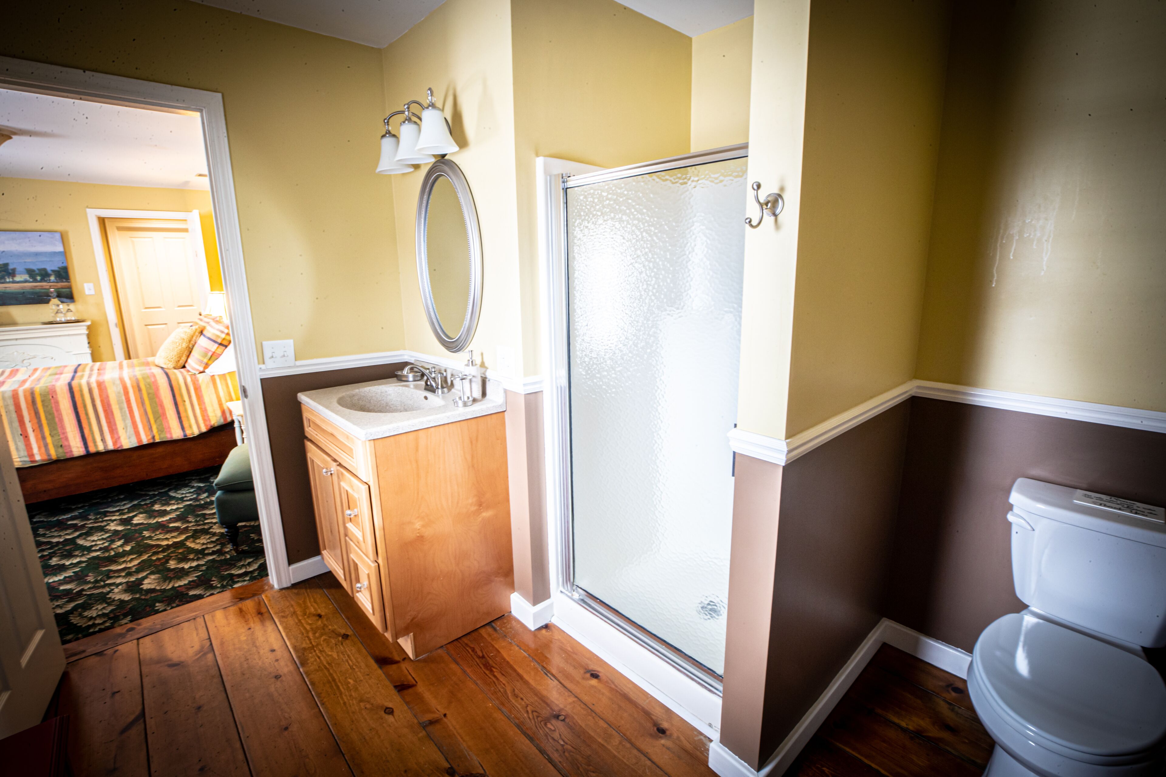 Un baño con ducha, inodoro, lavamanos y espejo.