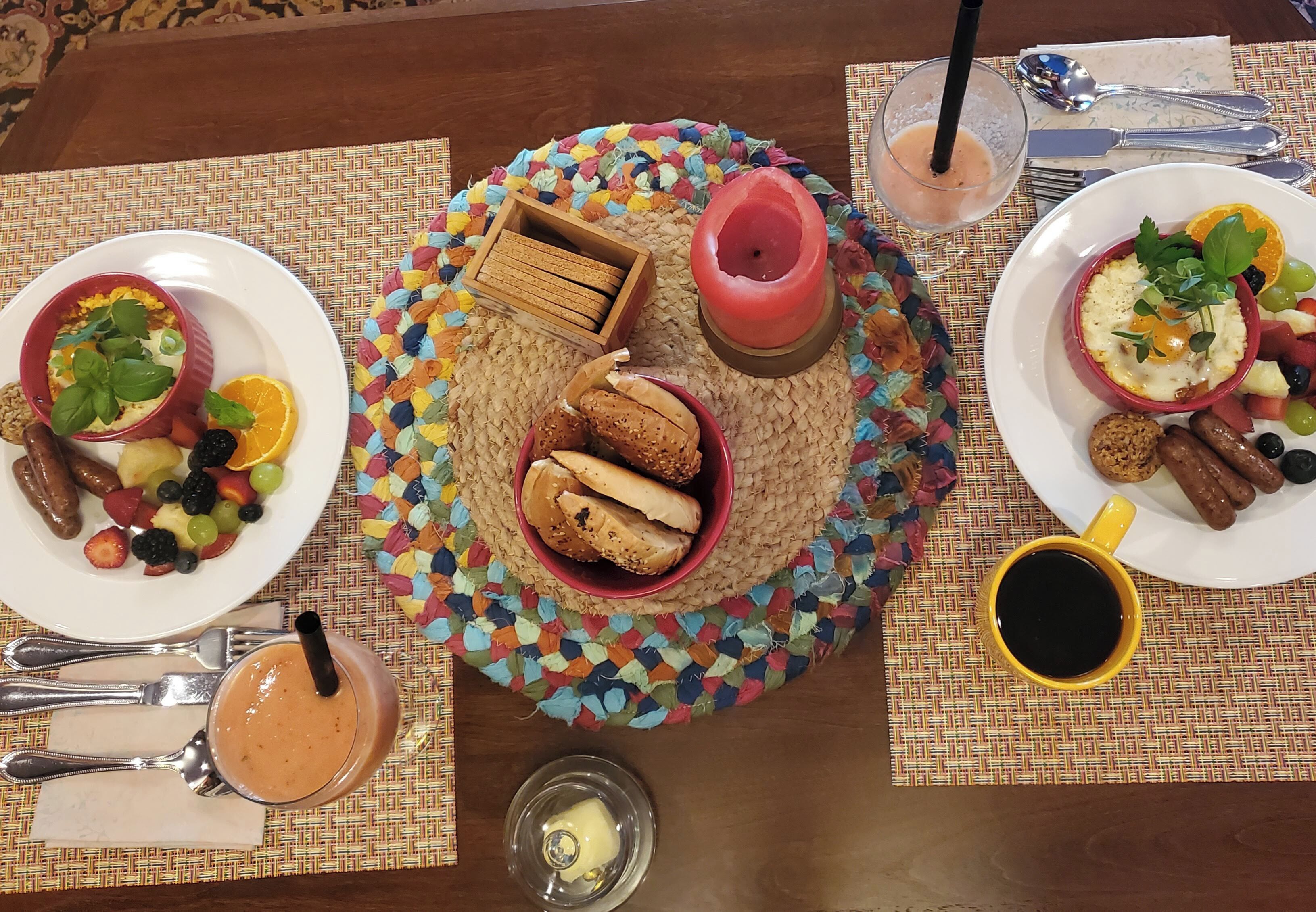 Una mesa de desayuno con diversos platos, una vela y cubiertos.