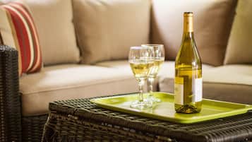 A wicker table with a green tray holding a wine bottle and two glasses.