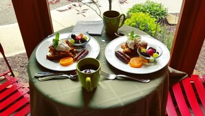 A table with two plates of food, a green mug, and a fork. - Twin Oaks Inn (Saugatuck)