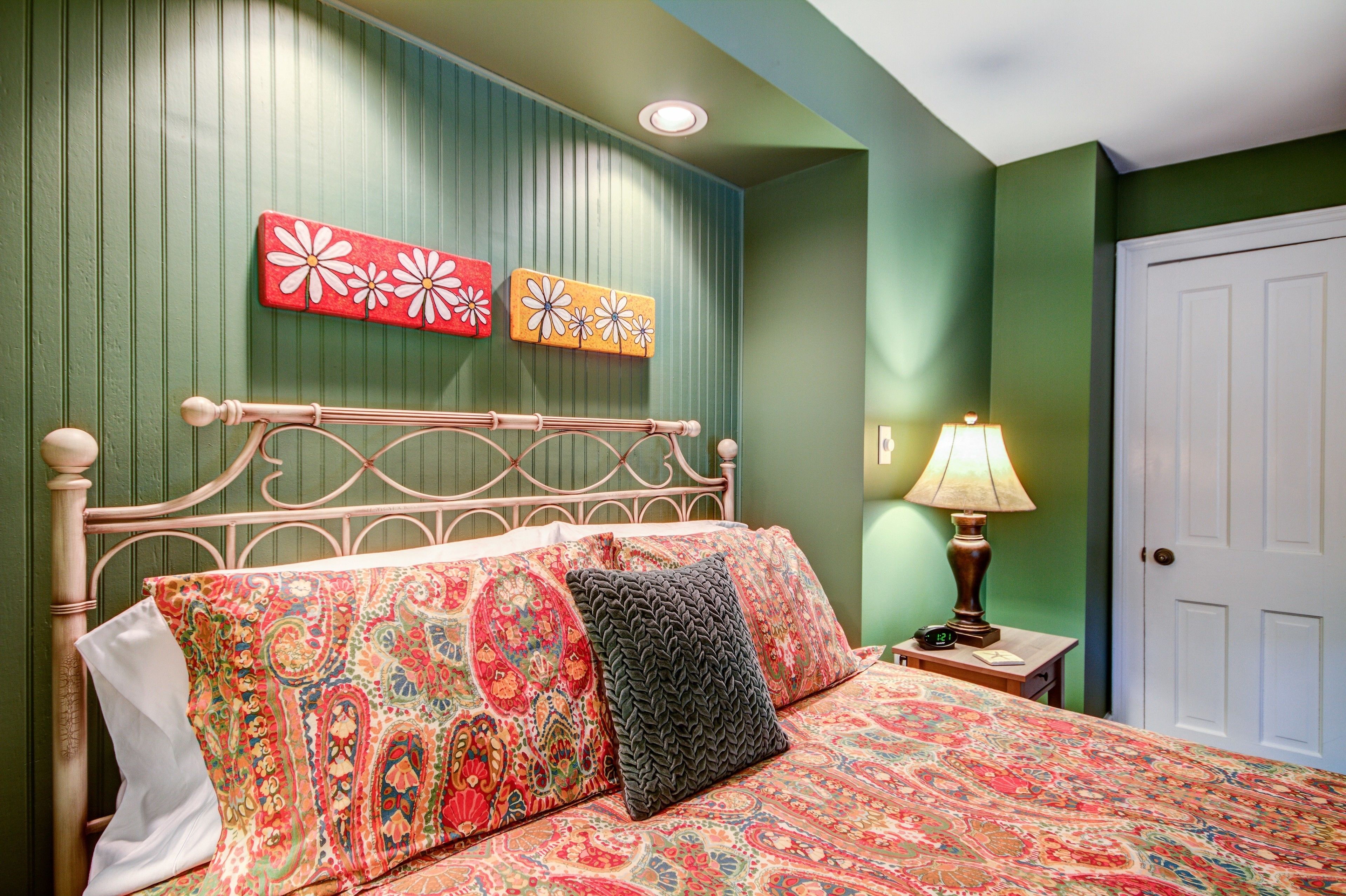 A bedroom with a bed, a nightstand, a lamp, and two wall art pieces.