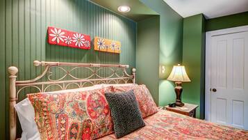 A bedroom with a bed, a nightstand, a lamp, and two wall art pieces.