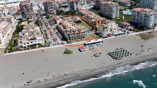 Vue aérienne d’une zone côtière comprenant une plage, des bâtiments et un espace délimité pour un événement particulier.