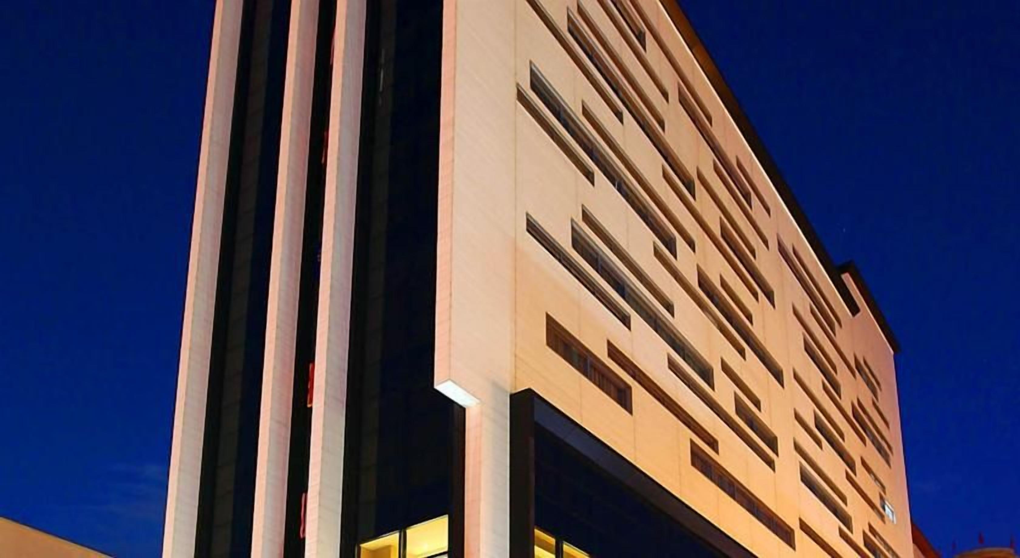 A modern building with a vertical design, featuring a series of windows and a flat facade.