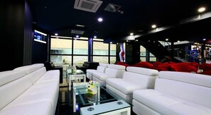Uma área de estar moderna com sofás brancos, uma mesa de centro de vidro e vista através de grandes janelas.