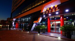 Entrada de hotel com design moderno, destacando uma placa com estrelas e a palavra 'HOTEL'.