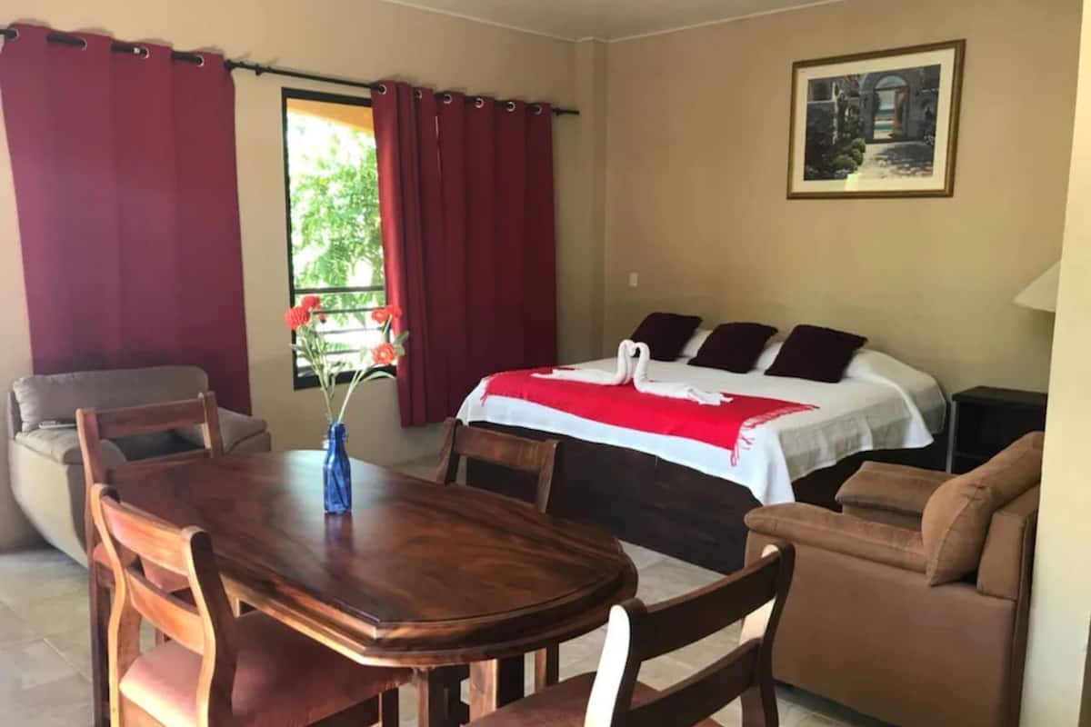 A hotel room with a bed, a dining table, and a sofa.