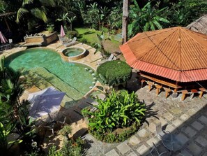 A pool area with a hot tub, a covered seating area, and lush greenery. - Hotel Loft Pacifico (Jacó)