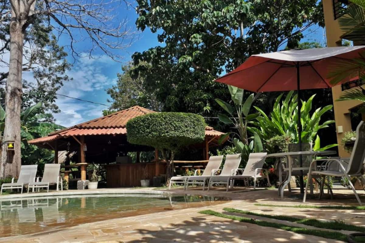 A pool area with lounge chairs and a covered seating area.
