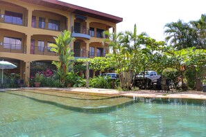 A hotel with a pool, outdoor seating, and a multi-story building with balconies. - Hotel Loft Pacifico (Jacó)
