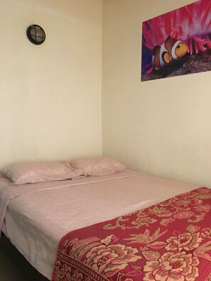 A single bed with a pink bedspread and a red floral-patterned blanket. - Apartotel Conchita (Jacó)