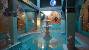A pool area with a central fountain, tiled walls with intricate designs, and stone lion statues. - McMenamins Old St. Francis (Bend)
