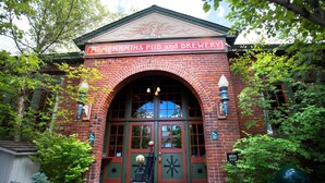 A brick building with a large arched entrance, a sign reading "McMenamins Pub and Brewery," and a wheelchair accessibility symbol. - McMenamins Old St. Francis (Bend)