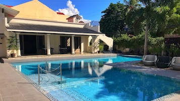 Een buitenzwembad, parasols bij het zwembad en ligstoelen