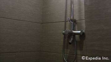 A shower with a handheld showerhead and a wall-mounted faucet in a tiled bathroom.