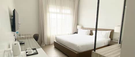 A hotel room with a bed, a bed, a desk, a chair, a mirror, and a window with curtains.