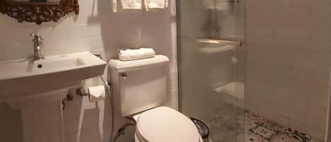 A bathroom with a toilet, sink, and shower area.