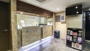 Un espace d’accueil doté d’un comptoir en marbre, d’un téléviseur fixé au mur et d’un présentoir à magazines.