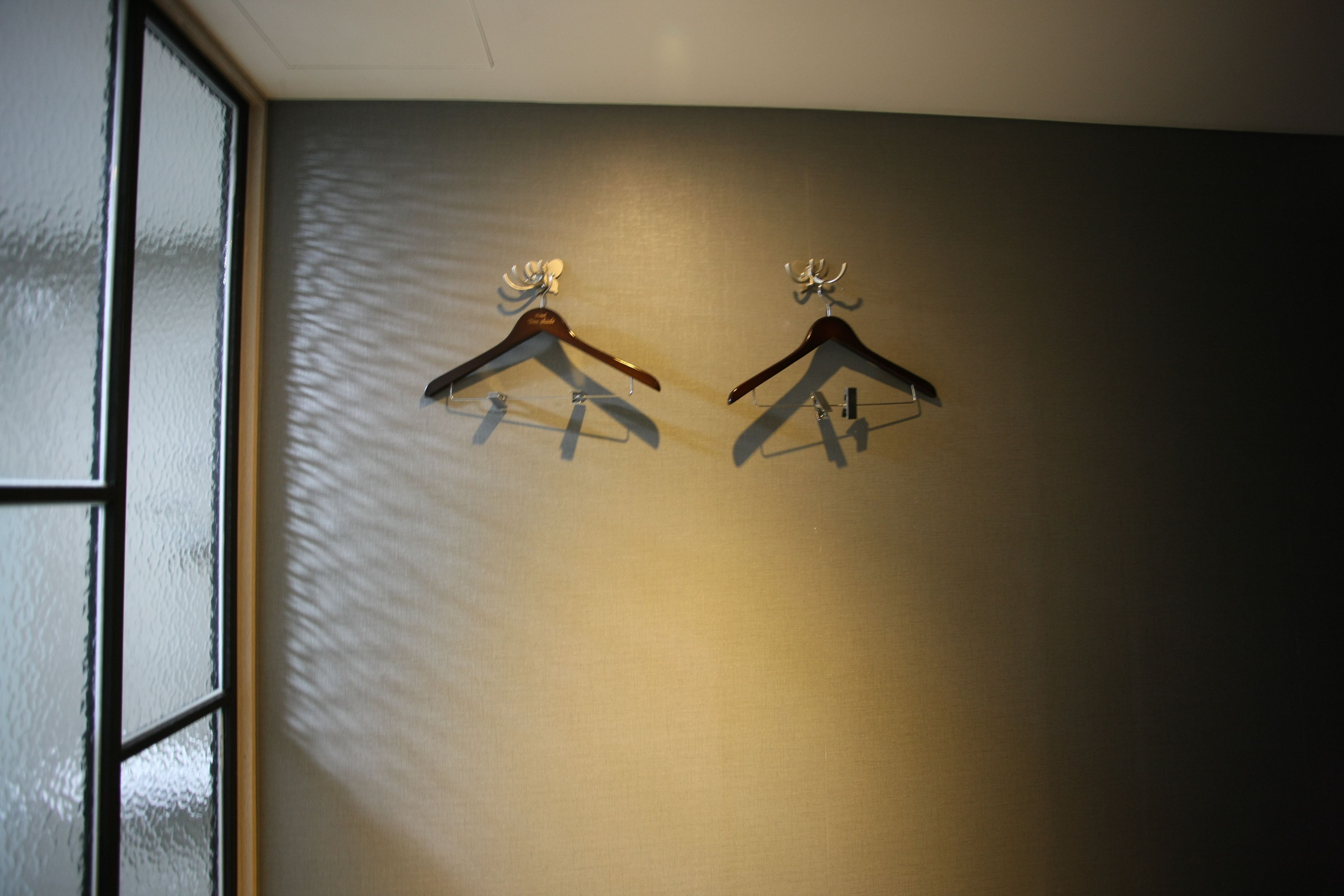 Dos perchas de madera en una pared con superficie texturizada.