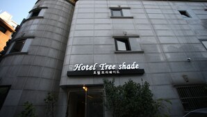 Un bâtiment arborant une enseigne indiquant « Hôtel à l’ombre des arbres » et présentant un design architectural moderne.