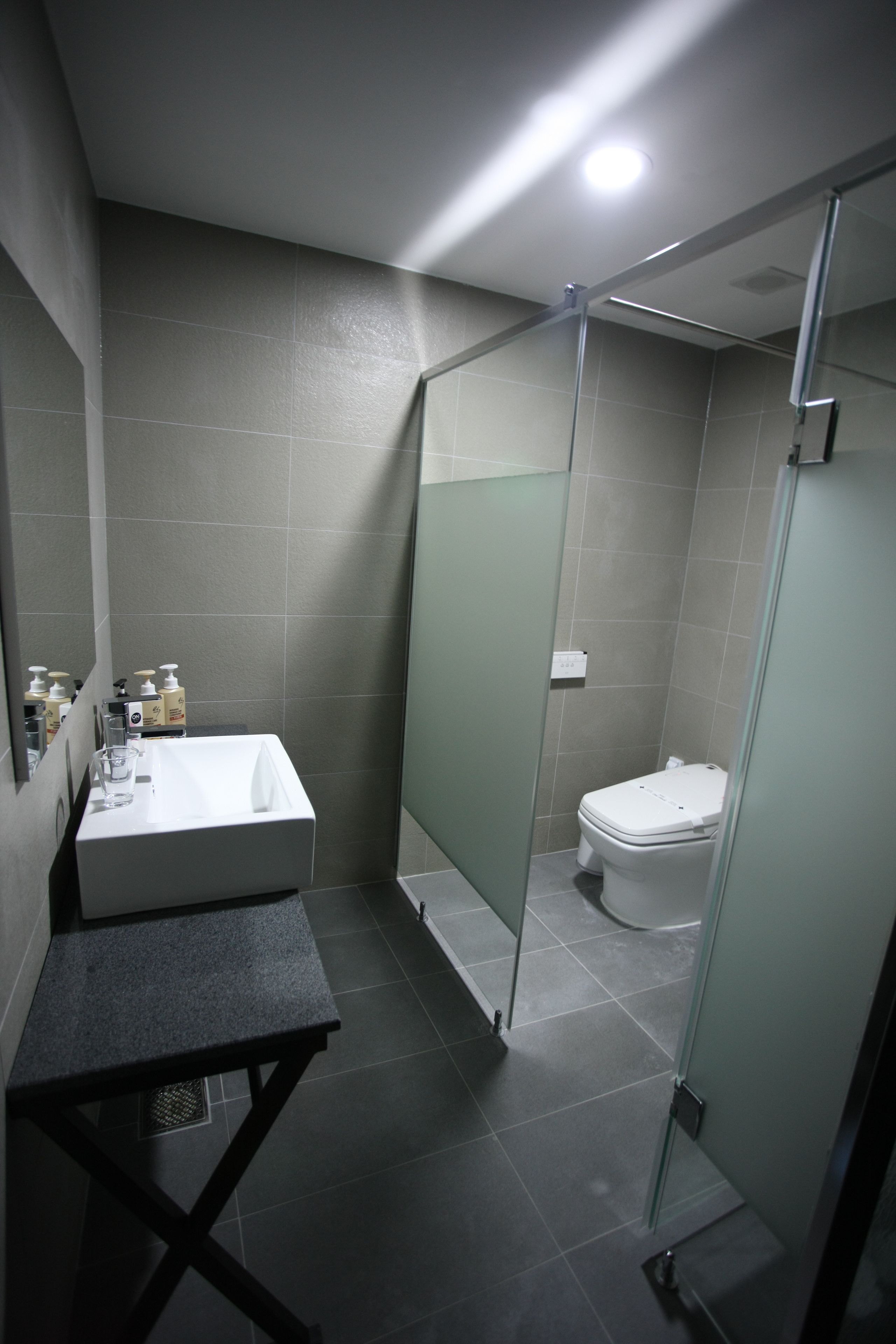 A modern bathroom with a glass-enclosed shower, a white bathtub, and a sink with toiletries.