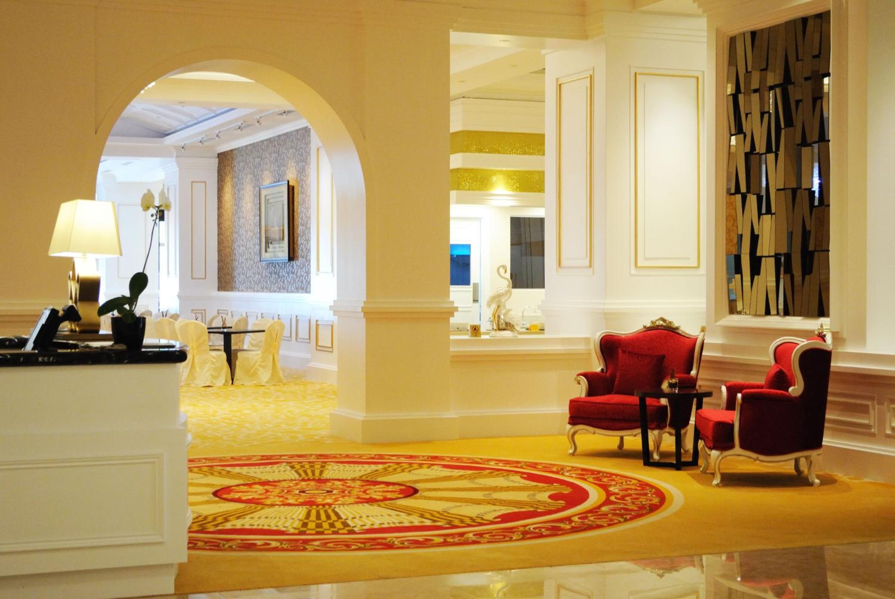 A lobby with a red carpet, red chairs, and a reception desk.