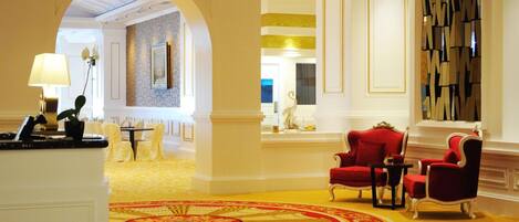A lobby with a red carpet, red chairs, and a reception desk.
