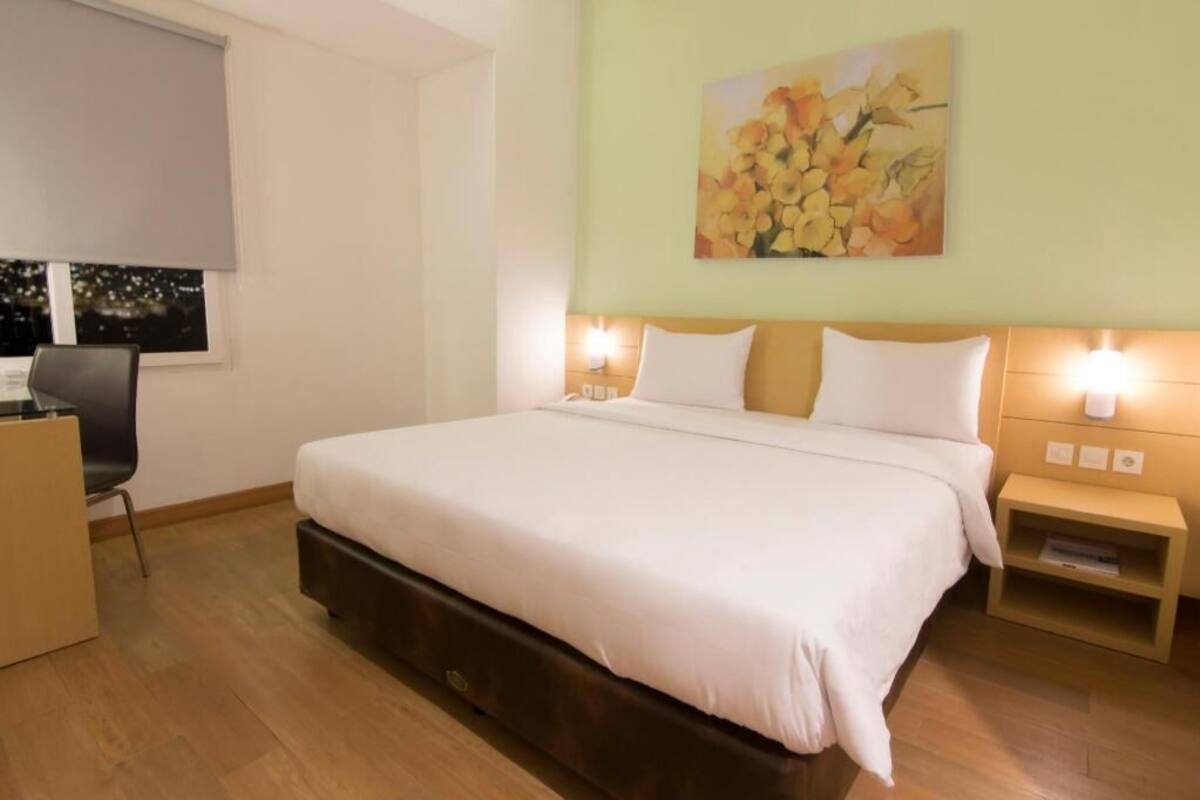 Une chambre d’hôtel avec un grand lit, des lampes de chevet, une table de chevet, un bureau et une chaise.