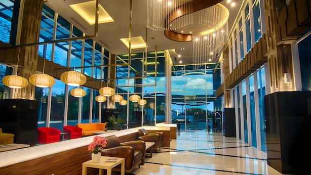 Eine moderne Hotelhalle mit Empfangstresen, Sitzgelegenheiten und großen Fenstern.