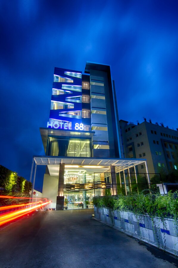Un hôtel moderne, reconnaissable à son grand panneau lumineux « HOTEL 88 », à son entrée en verre et à sa façade bien éclairée.