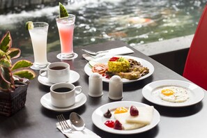 Une table dressée pour le petit-déjeuner, avec des œufs, des toasts et une assiette de fruits, ainsi que des boissons et des condiments.