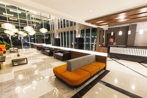 Un hall d’entrée moderne avec un comptoir d’accueil, un espace salon et de grandes fenêtres.