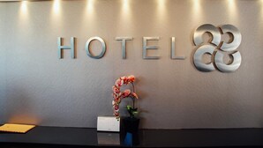 Ein Empfangsschalter mit einem Schild, auf dem 'HOTEL 88' steht, und einer Topforchidee.
